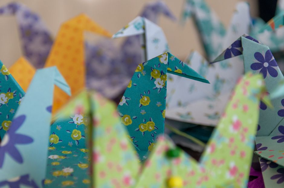 Close-up view of vibrant origami cranes with floral patterns, showcasing intricate paper art.