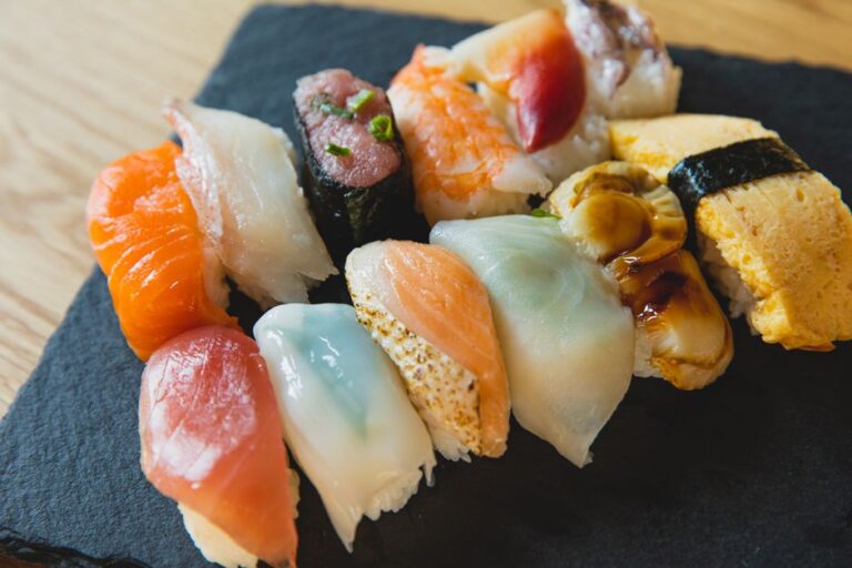 From above of assorted traditional Japanese nigiri sushi with raw fish and egg crepe served on black tray
